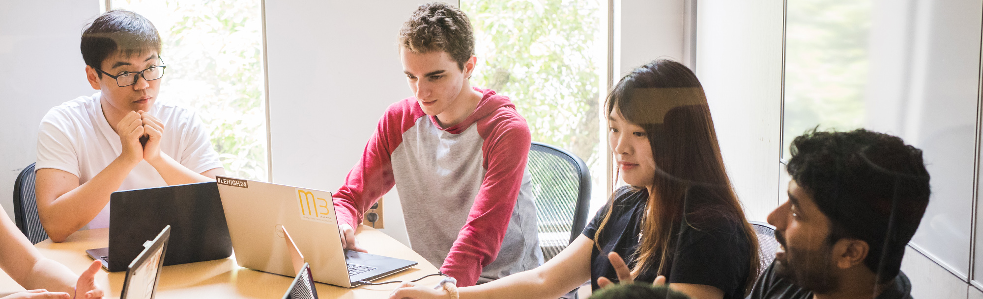 Four students working at laptops at a table